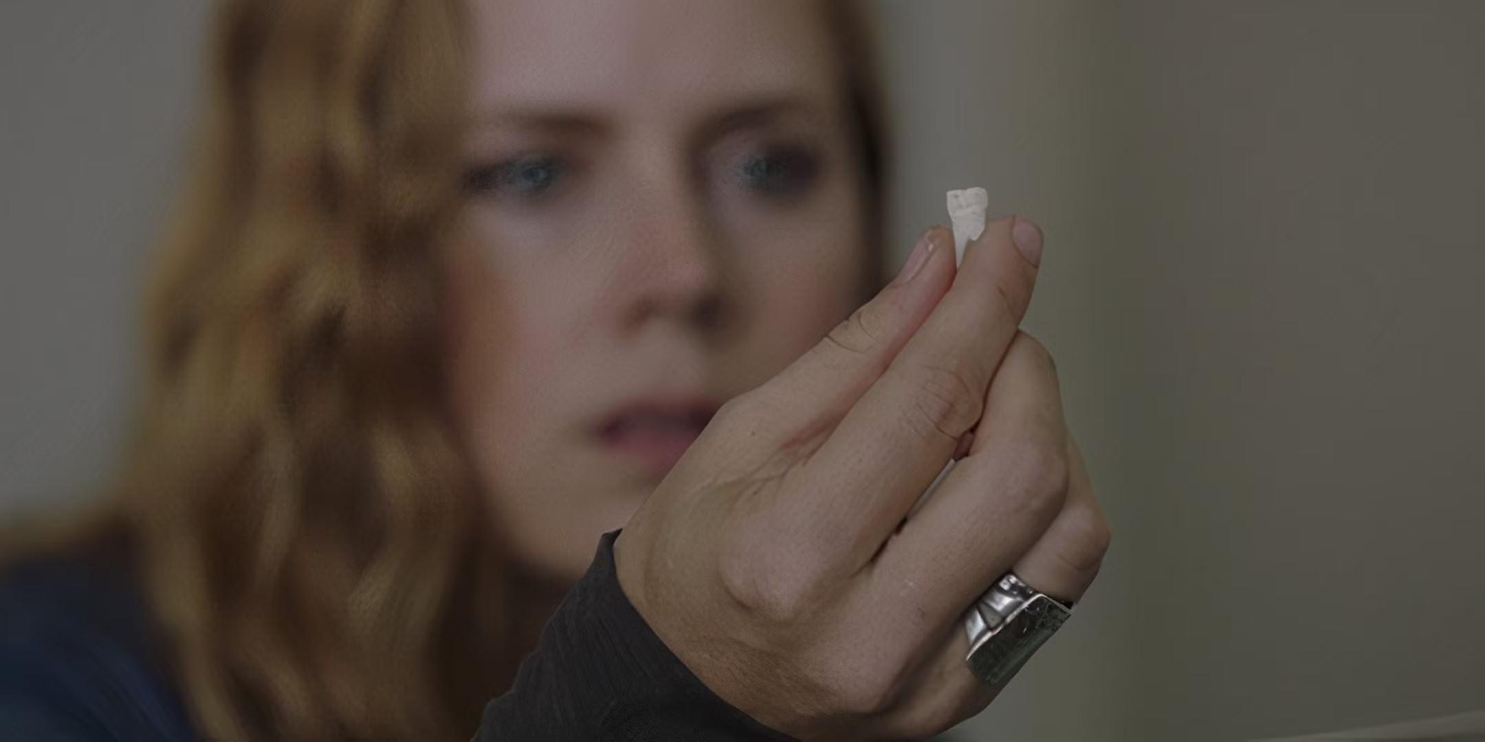 Amy Adams holding a tooth in the final episode of Sharp Objects - بهترین سریال هیجان انگیز پایان یافته