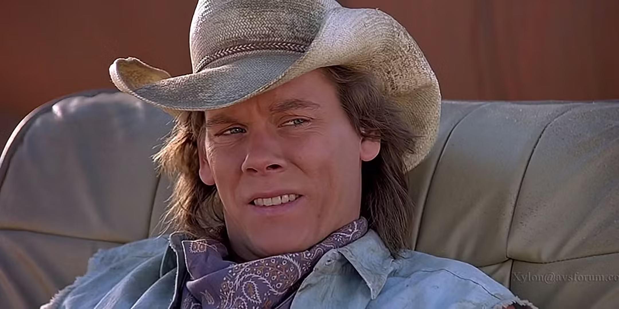 بهترین فیلم های ترسناک دهه 90: Kevin Bacon در نقش Val که در Tremors با حالتی نامطمئن روی صندلی نشسته است