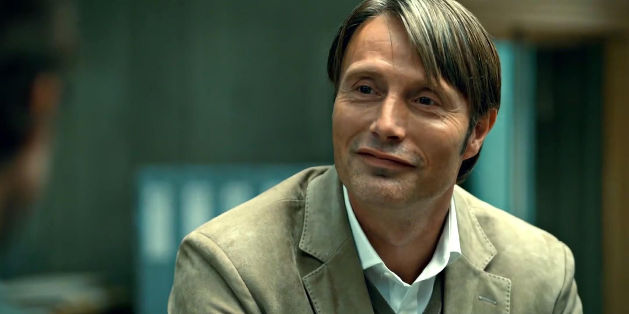 Mads Mikkelsen's Hannibal smiling at someone in Hannibal - بهترین سریال هیجان انگیز پایان یافته