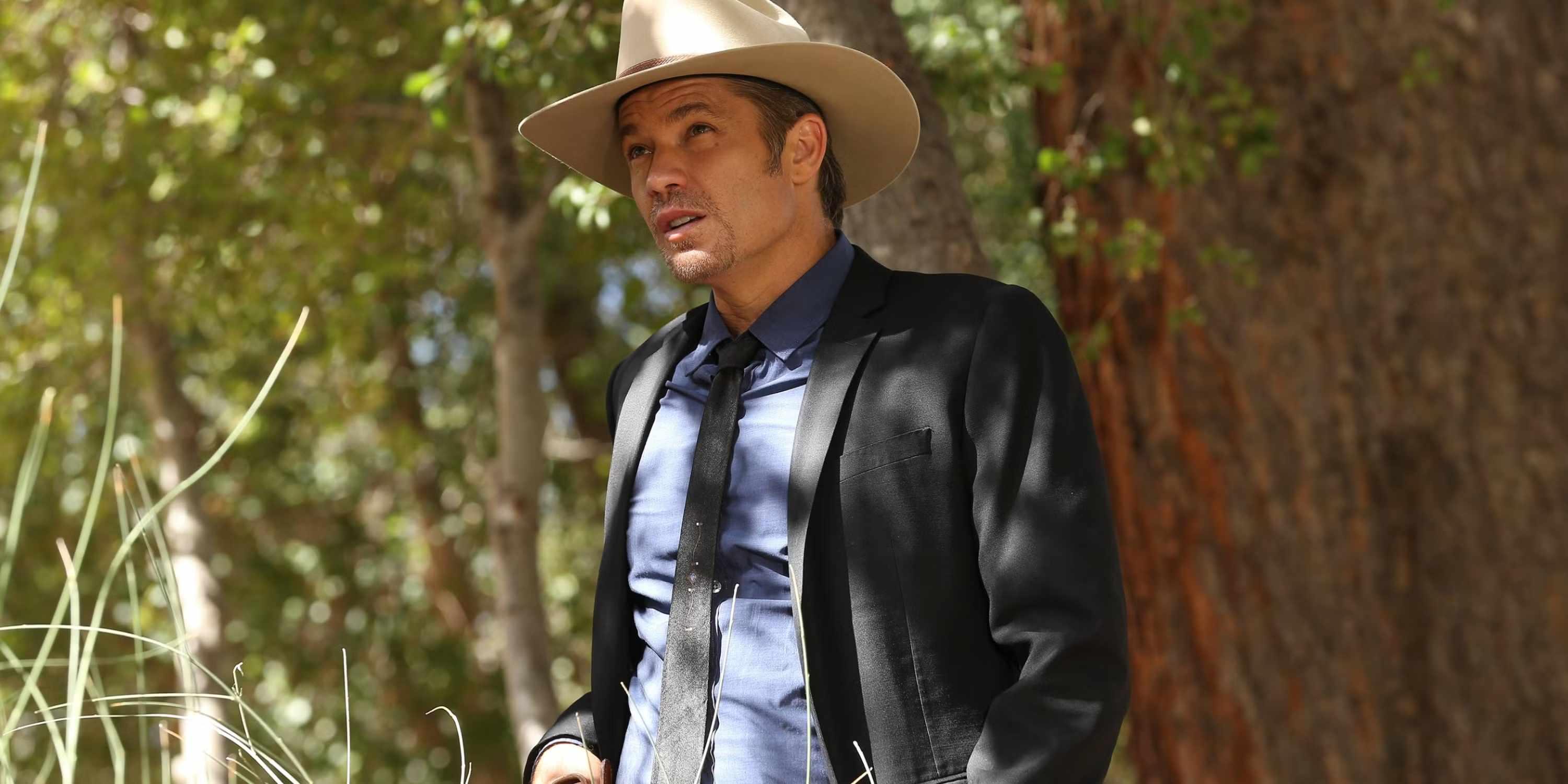 تیموتی اولیفانت در نقش ری لن گیونز در Justified ایستاده در بیرون با ظاهری جدی، از بهترین سریال اکشن Hulu