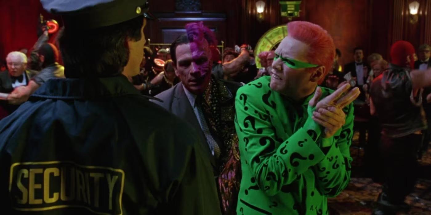 تامی لی جونز در نقش Two-Face و جیم کری در نقش Riddler در حال نگاه کردن به یک افسر پلیس در Batman Forever، از بهترین کاراکترهای منفی Batman