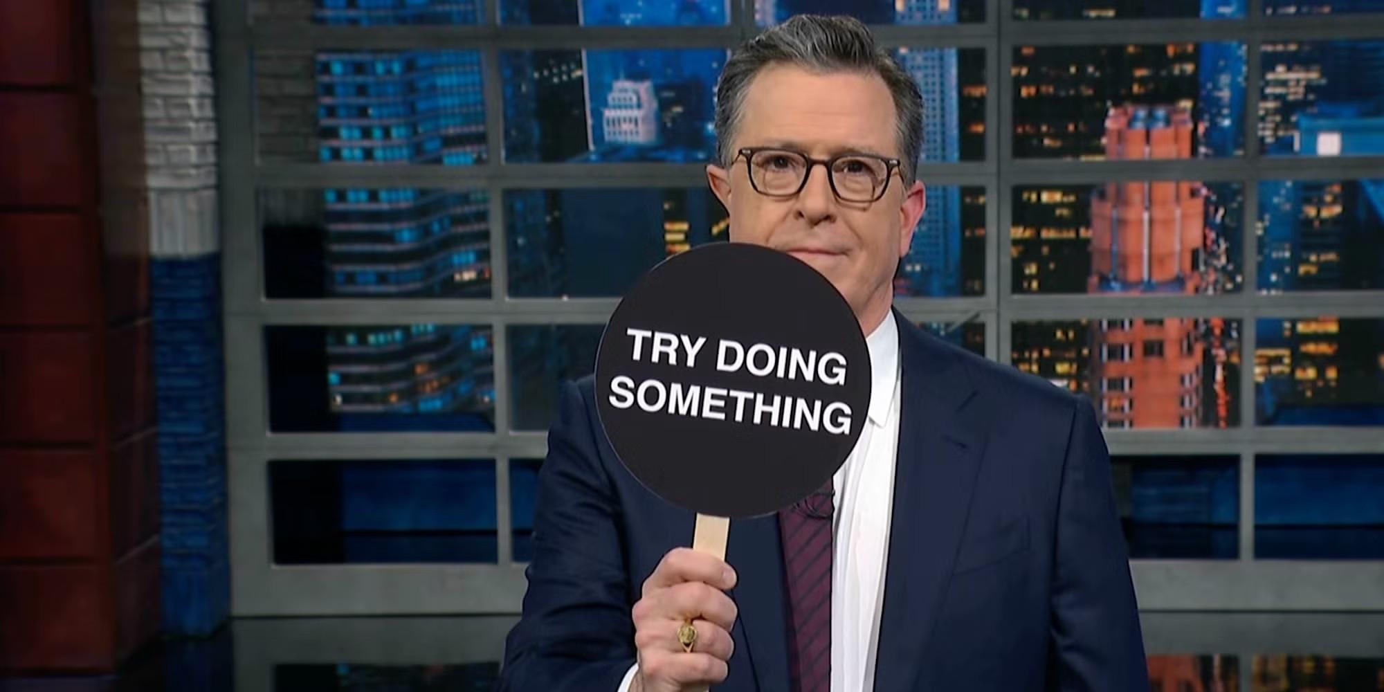 استیون کولبرت برنده Emmy در حال بالا گرفتن پدالی که روی آن نوشته شده Try Doing Something on The Late Show