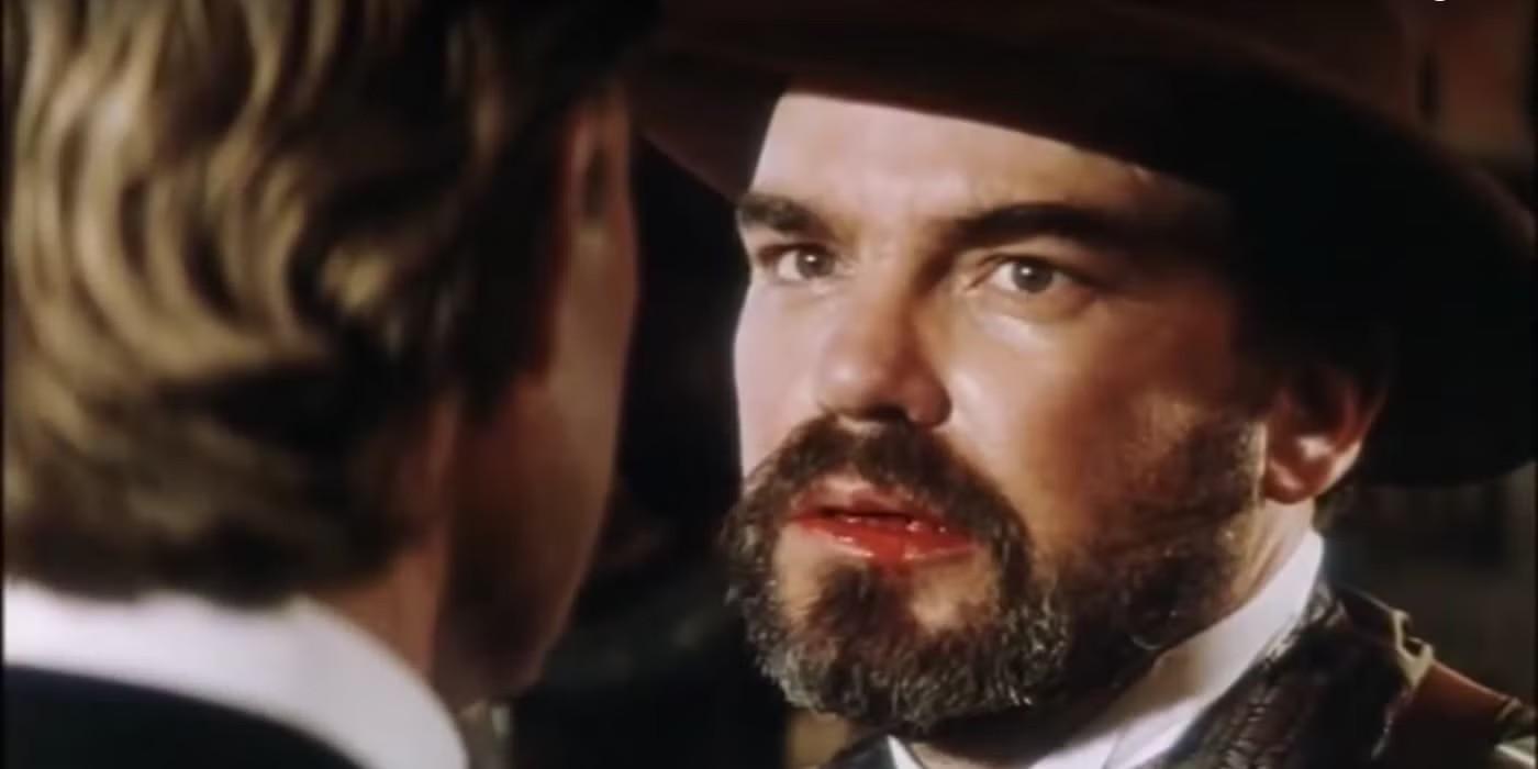 بیلی باب تورنتون با لب خونی و عصبانی در Tombstone، یکی از بهترین فیلم های Billy Bob Thornton
