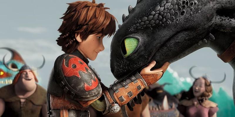 هیکاپ (Hiccup) سر بی دندان (Toothless) را در دست هایش در How to Train Your Dragon 2 (2014) گرفته است.