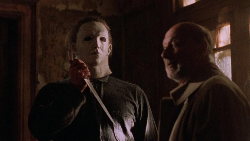 بهترین فیلم های Halloween: مایکل مایرز در حال نگه داشتن چاقو در کنار دکتر لومیس در فیلم Halloween 5: The Revenge of Michael Myers.