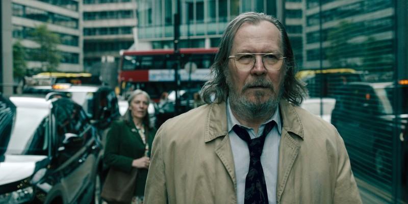 جکسون لمب (گری اولدمن) در حال قدم زدن در خیابان ها در فصل 5، قسمت 3 سریال Slow Horses، نشان دهنده Jackson Lamb Slow Horses گذشته.
