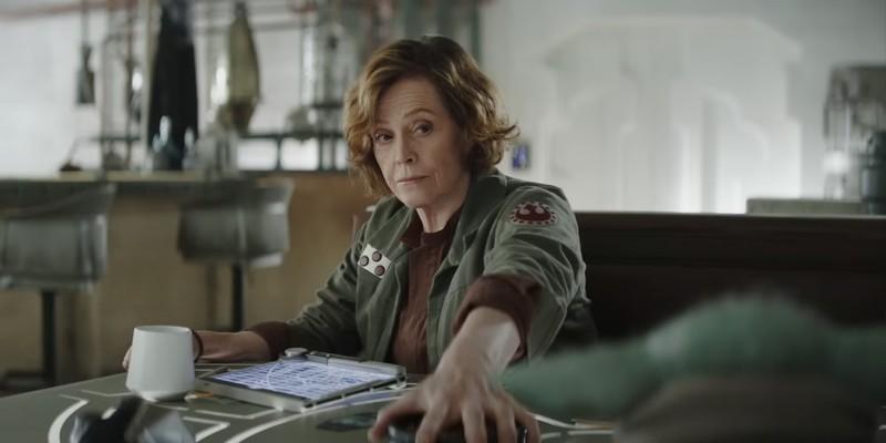 Colonel Ward (Sigourney Weaver) from The Mandalorian and Grogu راه حل Star Wars holds a bowl of snacks away from Grogu.