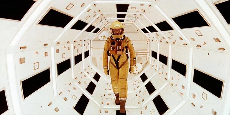 یک فضانورد با لباس فضایی زرد در حال عبور از یک راهروی بلند و سفید در 2001: A Space Odyssey, فیلم علمی تخیلی بهتر از Star Wars