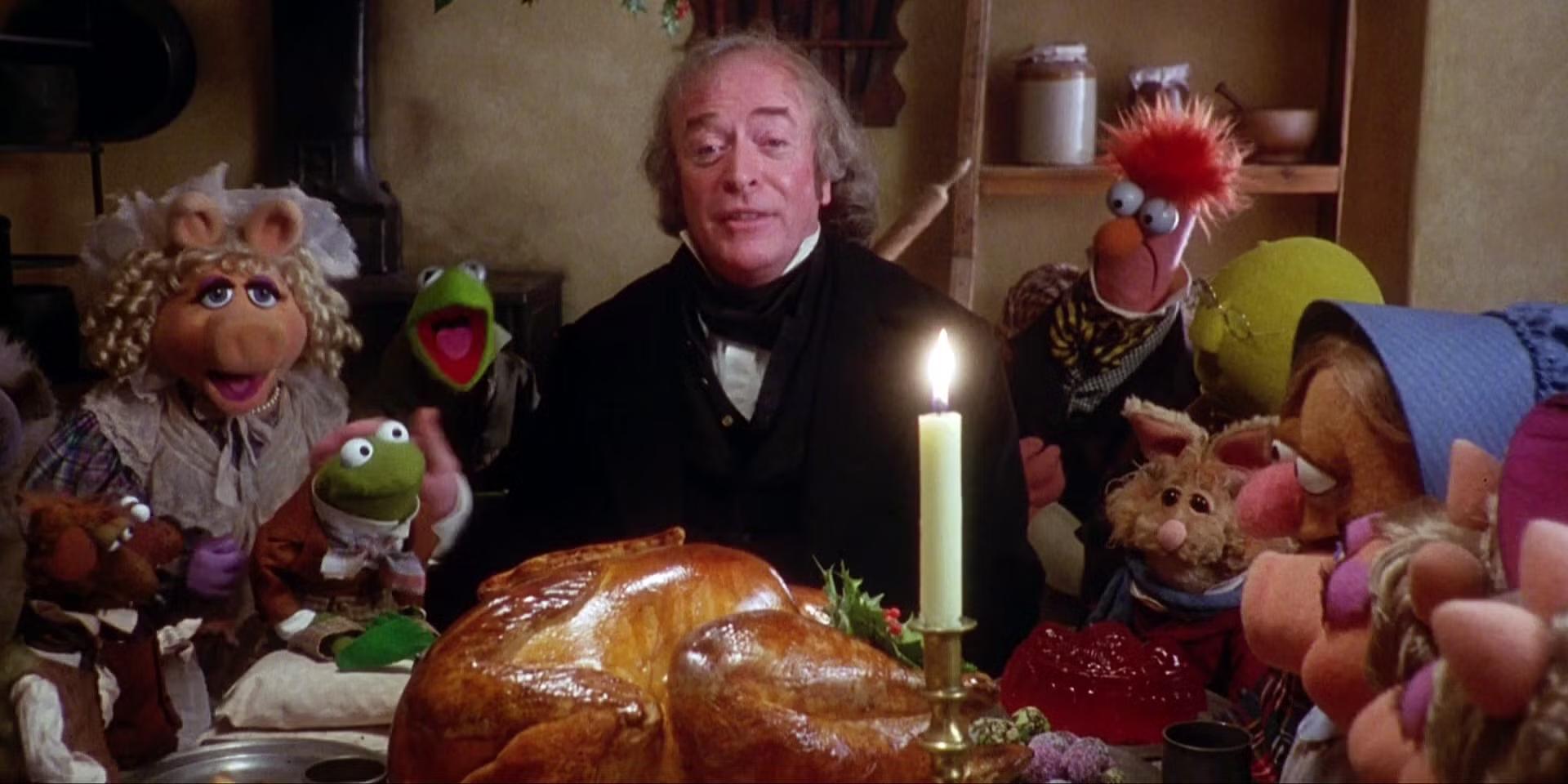 Ebeneezer Scrooge (Michael Caine) and the Muppets gathered around a Christmas turkey dinner in The Muppet Christmas Carol, از برترین فیلم های دیزنی دهه نود
