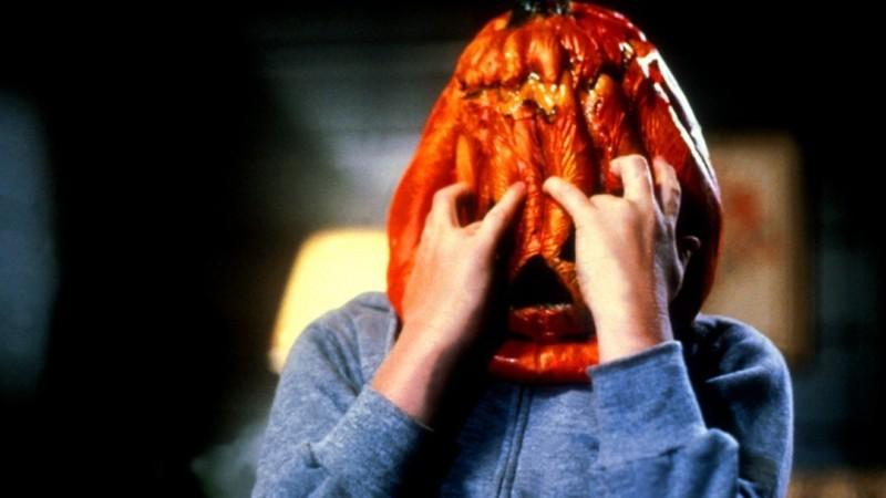 بهترین فیلم های Halloween: پسری جوان در حال پنجه کشیدن به ماسک کدو تنبلی که در طول فیلم Halloween 3: Season of the Witch پوشیده است.