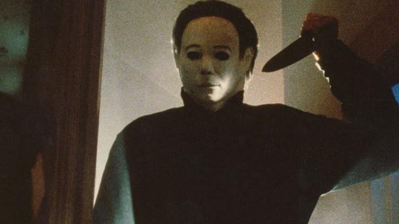 بهترین فیلم های Halloween: مایکل مایرز در حال نگه داشتن یک چاقوی بزرگ آشپزخانه بالای سرش در فیلم Halloween 4: The Return of Michael Myers