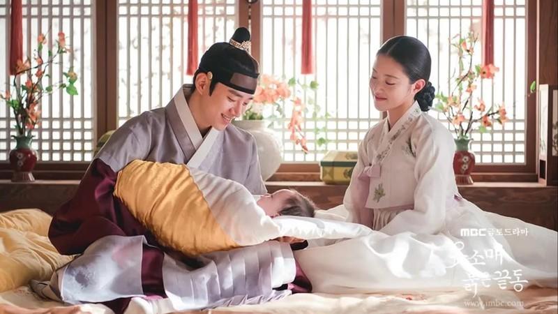 سریال کره ای مشابه Queen of Tears: مردی که نوزادی را در آغوش گرفته و زنی با لبخند در The Red Sleeve به او نگاه می کند