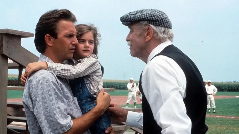 کوین کاستنر در فیلم Field of Dreams، از فیلم های غیر وسترن کوین کاستنر، در حالی که یک دختر کوچک را در آغوش گرفته، با مردی مسن تر صحبت می کند.