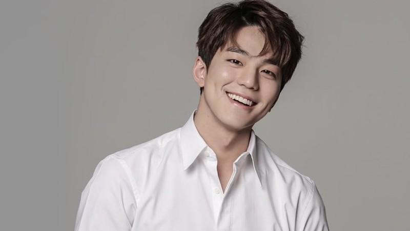 کیم مین-کیو، یکی از بازیگران مستعد برای بازگشت بازیگران K-drama، با پیراهن سفید لبخند می زند.