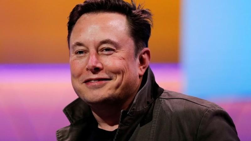 ایلان ماسک گیمر در حال لبخند زدن. یک پس زمینه رنگارنگ وجود دارد.